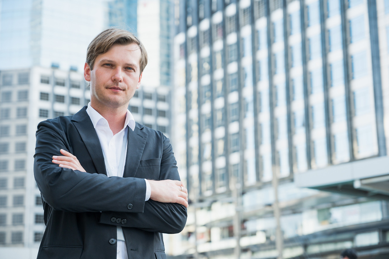 vecteezy_businessman-standing-with-arms-crossed-on-business-building-background_3351114.jpg