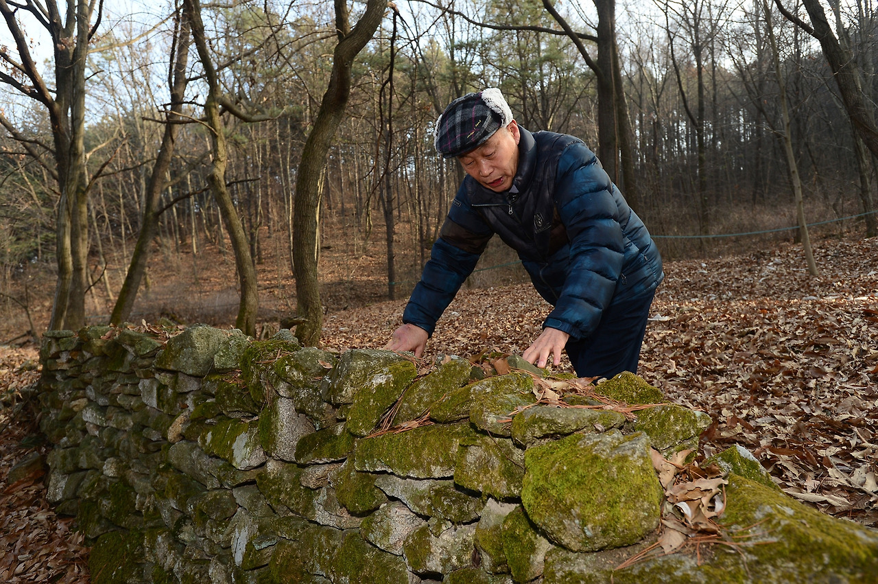 독립운동가 한훈 선생의 장손자인 한상회 씨가 조부의 집 터에 남아있는 돌담을 어루만지며 생각에 잠겨 있다.(사진제공 국방일보).jpg