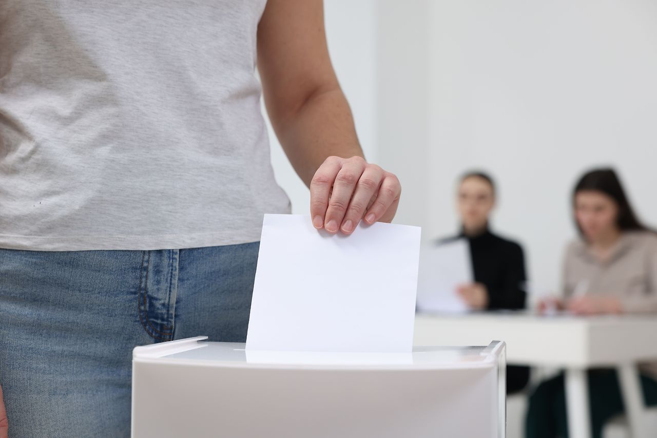 woman-putting-her-vote-into-ballot-box-blurred-background-closeup.jpg