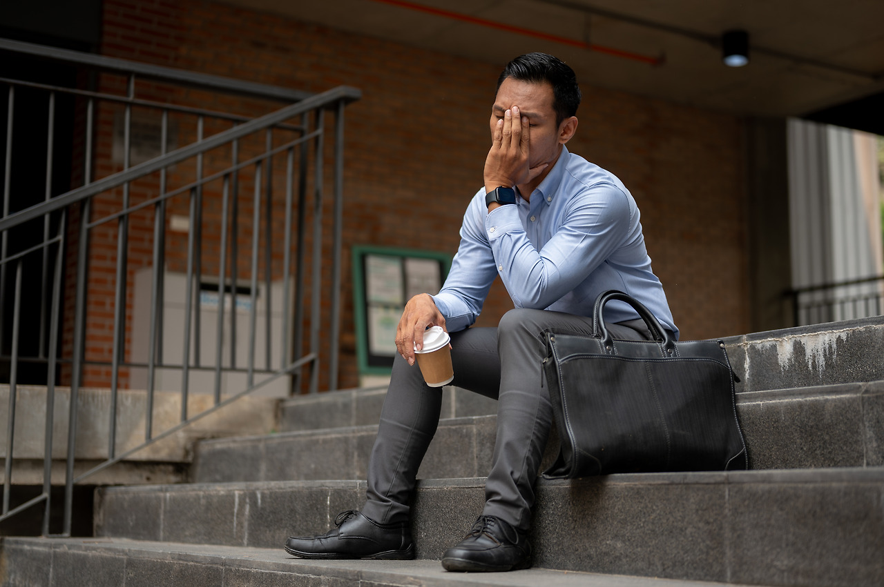stressed-asian-businessman-appearing-tired-unhappy-sits-steps-outside-building.jpg