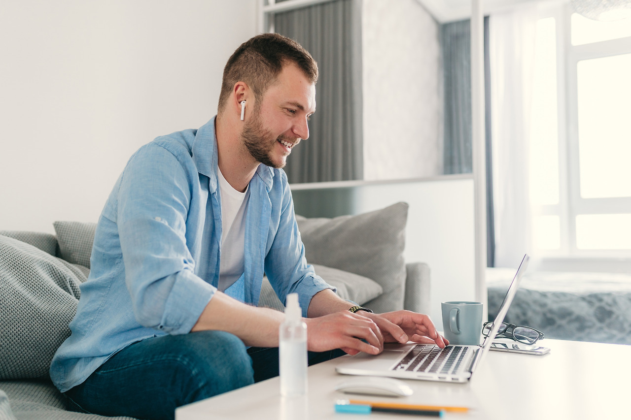 smiling-man-shirt-sitting-relaxed-sofa-home-table-working-online-laptop.jpg