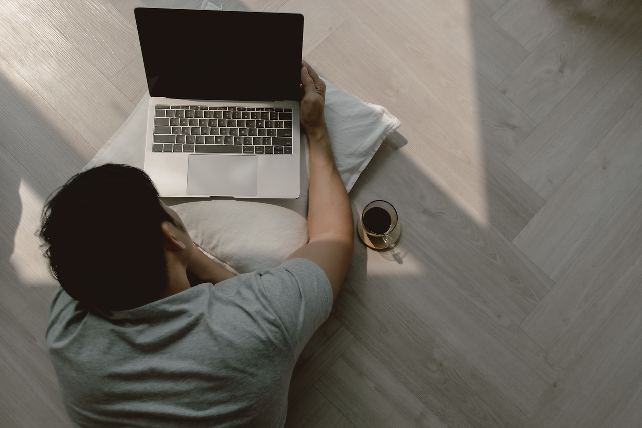 top-view-asian-man-using-computer-lying-floor-while-working-laptop-with-coffee-typing.jpg
