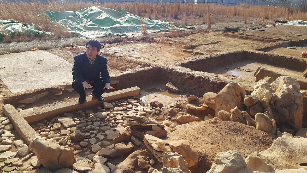 10-1 최맹식 전 국립문화재연구소장이 익산 왕궁리 유적 내 백제시대 ‘왕궁 정원 터’를 둘러보고 있다. 그의 발아래에 있는 직사각형 돌이 석축 수조로, 조경용 괴석을 타고 흘러내린 물이 이곳에 고였을 것으로 추정된다. 저자 .jpg