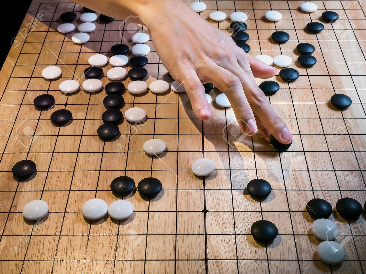 96271302-close-up-of-player-hand-make-a-move-in-go-game-weiqi-baduk-traditional-asian-strategy-board-game.jpg
