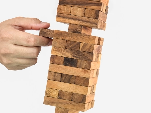inclined-wooden-block-tower-jenga-game-with-hand-risk-concept_1150-6155.jpg