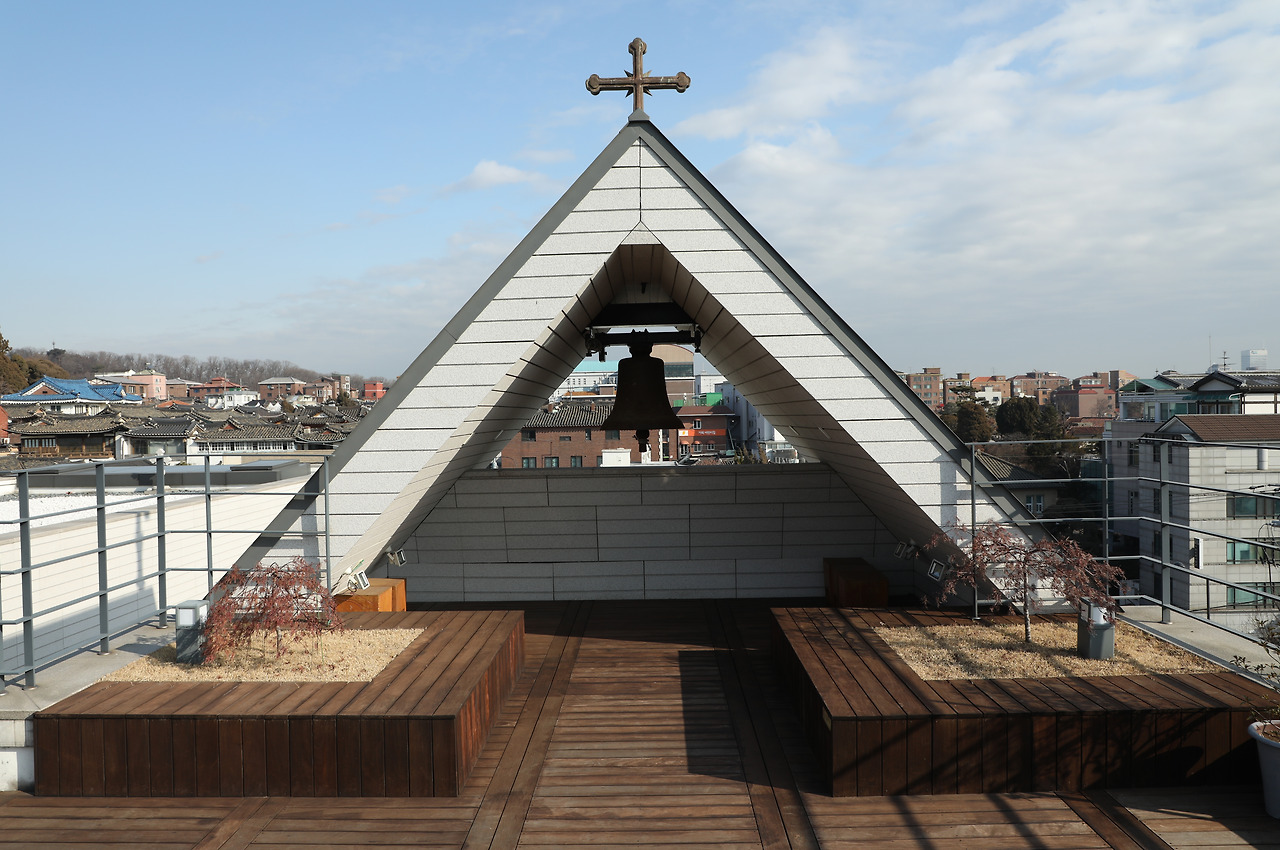 사진4_가회동 성당 꼭대기의 십자가와 동종. 십자가는 북촌 한옥마을 풍관에 스며들기 위해 아담하게 세워졌다. 1958년 독일에서 주조된 동종은 맑고 고운 소리를 지녔지만 옛 성당건물이 그 진동을 감당하기 어렵다 하여 타종하지 않는 전통을 지금도 계승하고 있다. ⓒ포스트픽.jpg