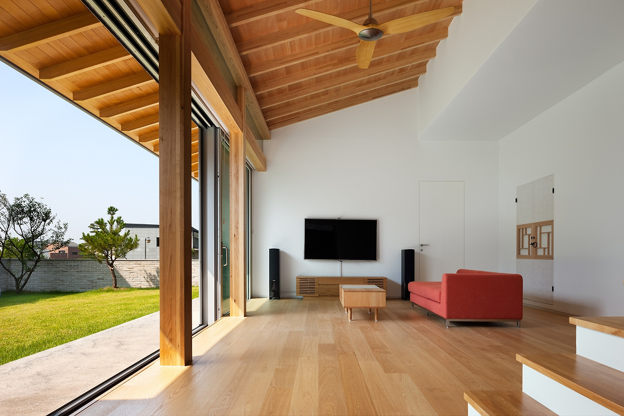 사진1_메인 후보 파주K주택의 거실과 정원. 대들보와 서까래는 없지만 경사진 목조지붕을 받치는 각(角)서까래 구조로 한옥의 대청과 안마당 느낌을 살려냈다.. ⓒ박영채.jpg