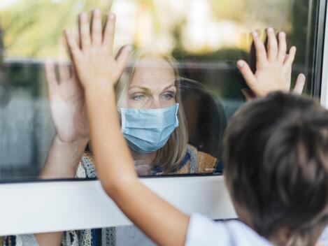 woman-with-medical-mask-home-saluting-nephew-through-window (1).jpg