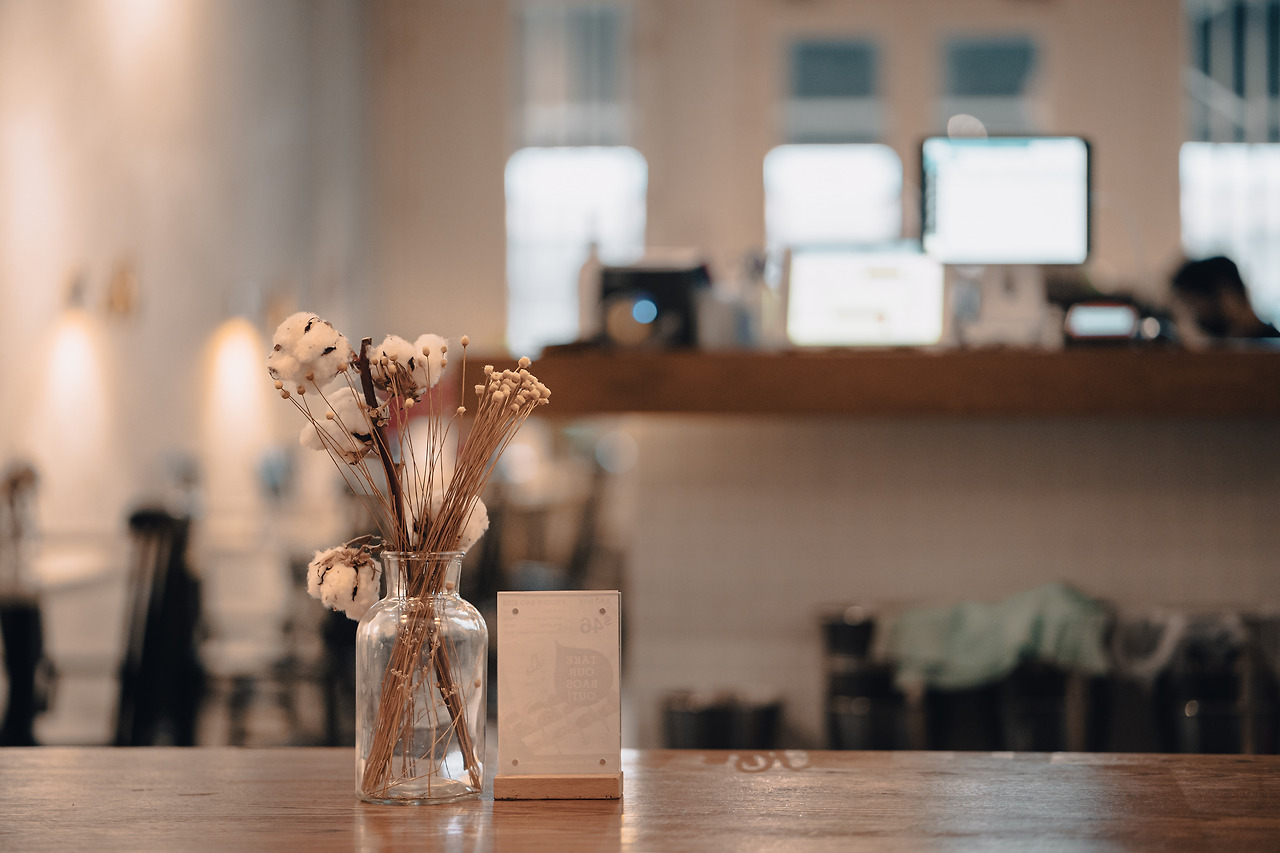 closeup-shot-cafe-wooden-table-with-jar-decorative-flowers-against-blurred-background.jpg