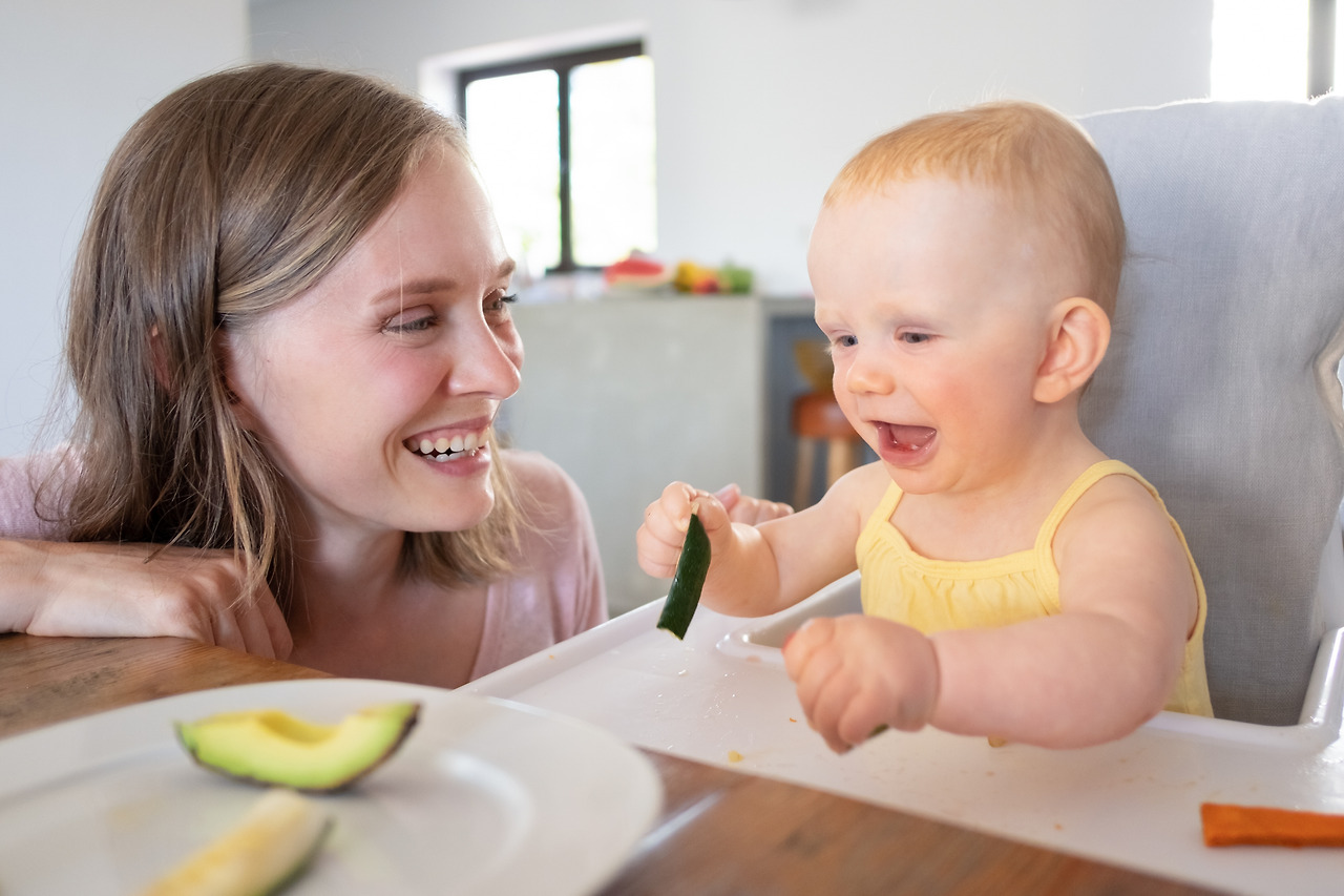 joyful-mom-watching-baby-eating-solid-food-high-chair-laughing-having-fun-closeup-shot-child-care-nutrition-concept.jpg