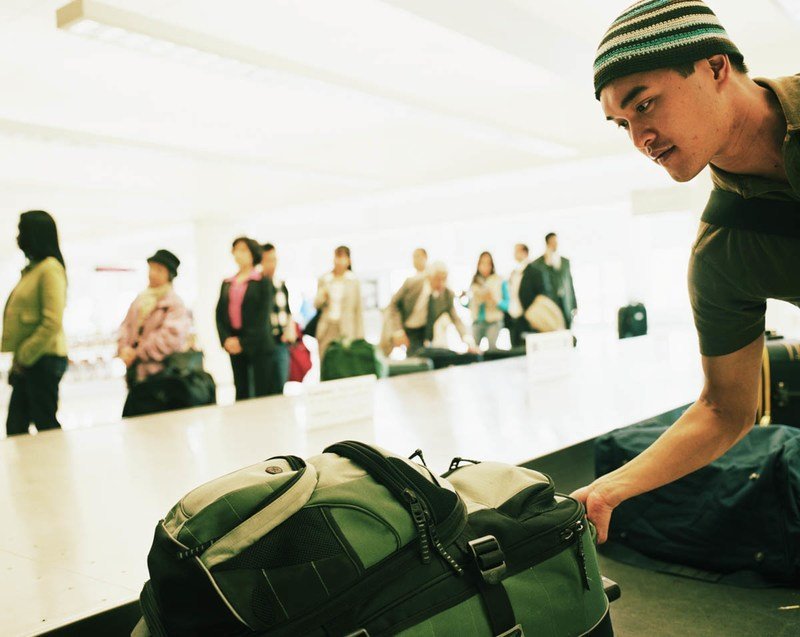 man-picking-up-a-suitcase-from-conveyer-belt.jpg
