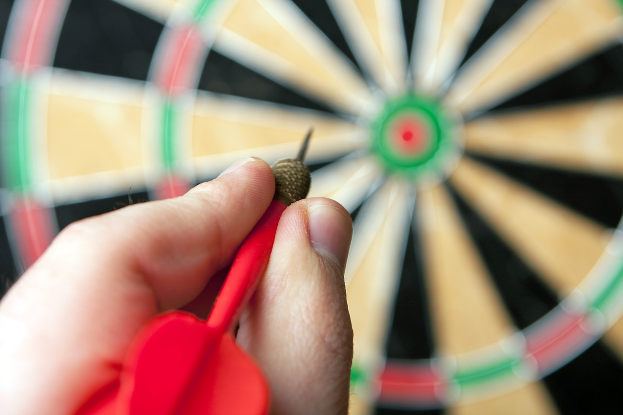 a-hand-holding-a-dart-getting-ready-to-aim-at-the-dartboard-shallow-depth-of-field_SFzyd0Ho.jpg
