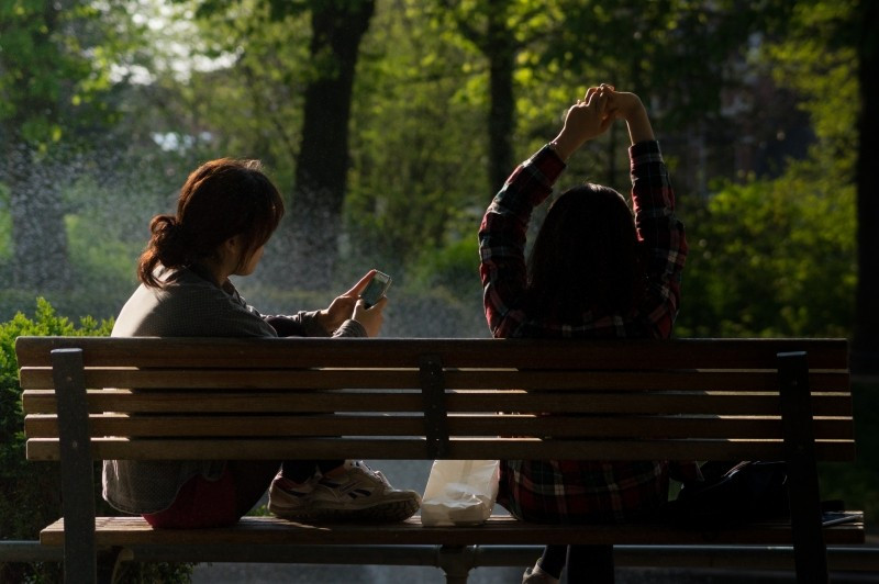 female-friends-relaxing-on-bench-in-park.jpg