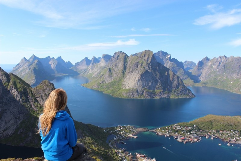 young-blonde-woman-sitting-on-rock-and-looking-at-mountains-and-lake.jpg