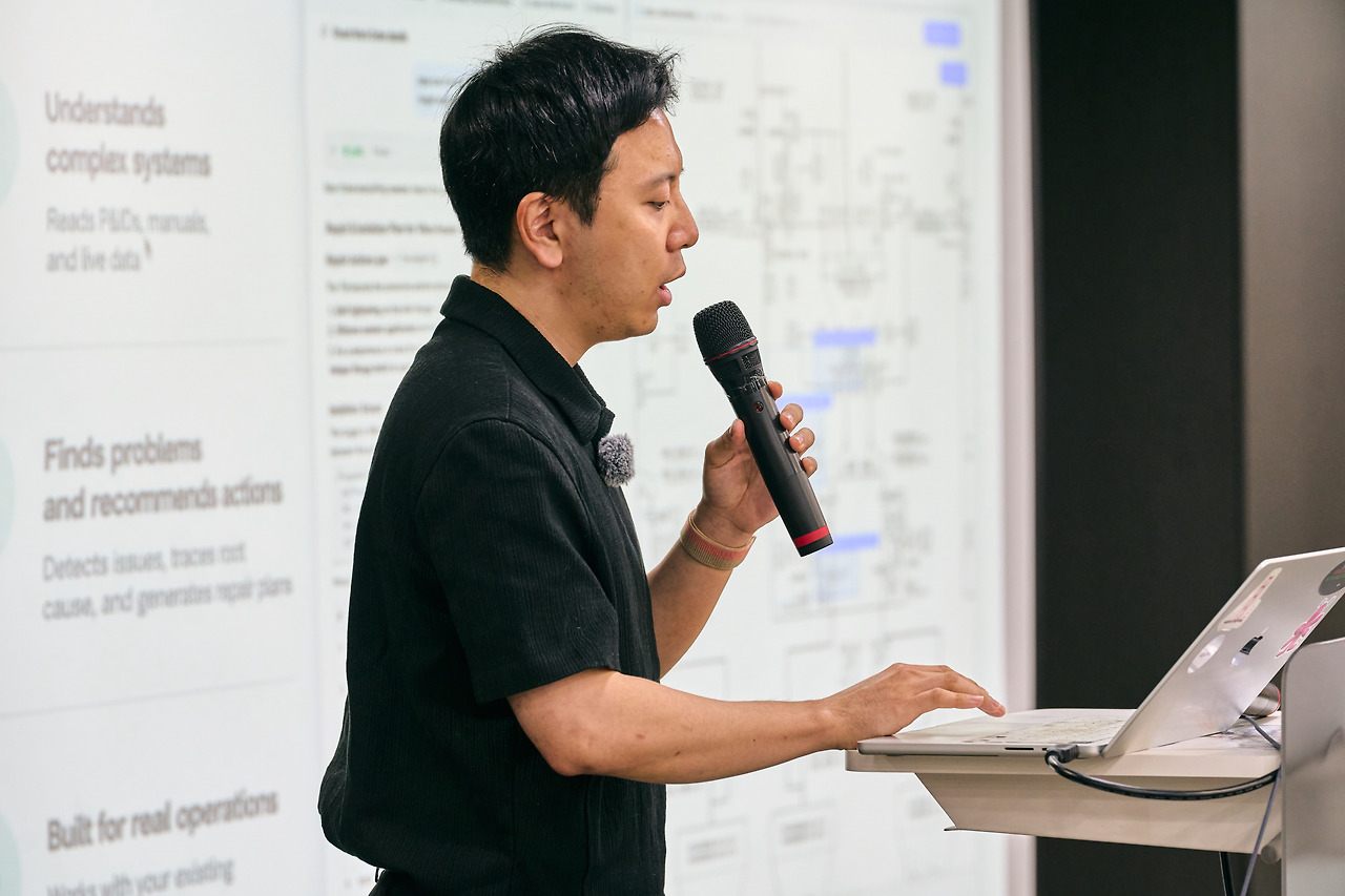 A presenter speaking beside a projected plant P&ID diagram, the slide listing what the agent reads and recommends.