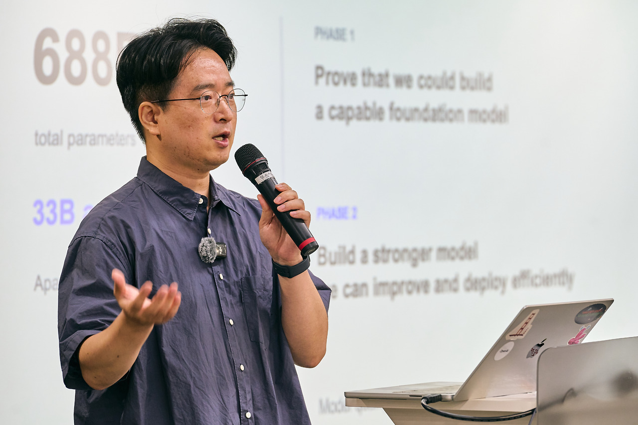 A presenter with a mic in front of a slide reading '688B total parameters' and a two-phase model roadmap.