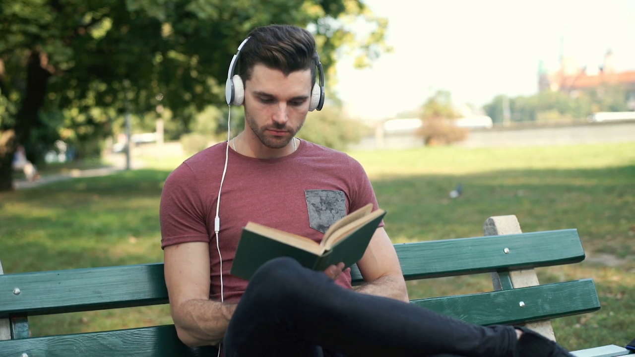 handsome-man-listening-music-and-reading-book-while-sitting-in-the-park_r4wmmhrfl_thumbnail-full01.png