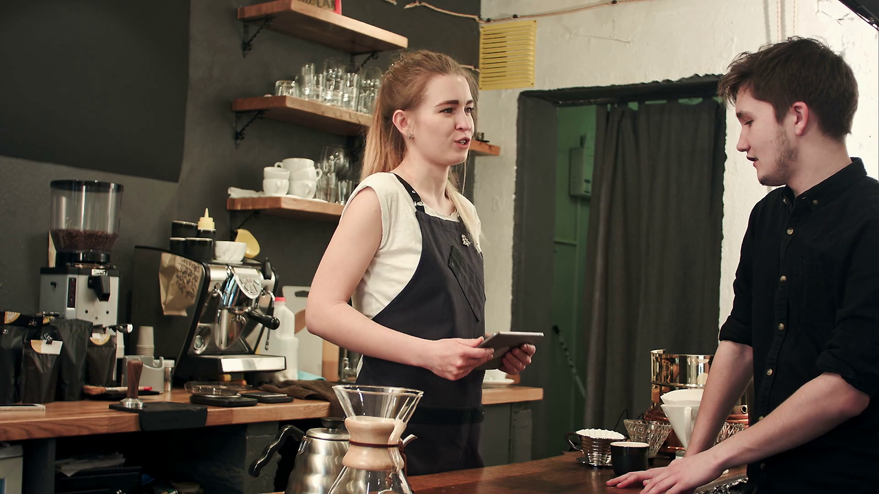videoblocks-female-barista-talking-to-customer-in-a-cafe-taking-order_rx3-arwg_thumbnail-full01.png