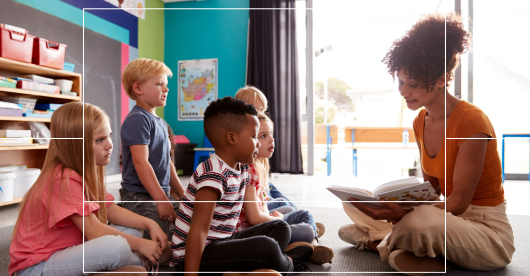 A teacher smiling as she teaches children.png