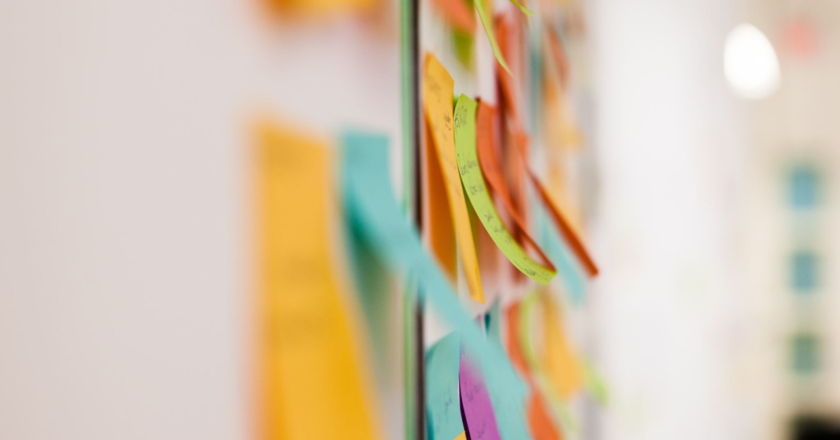 Create a minimalistic design of a white wall with several pastel-colored post-its attached to.png