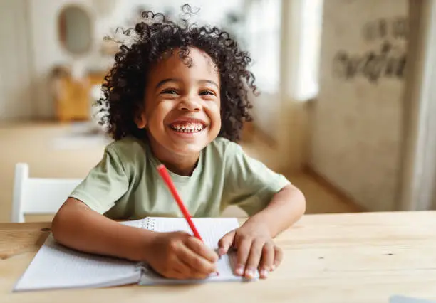 smiling-african-american-child-school-boy-doing-homework-while-sitting-at-desk-at-home.jpg?s=612x612&w=0&k=20&c=J31K4oWAEcv_COW7BXX6Dm1uIo3VWiUEM2CmReHpt6U=
