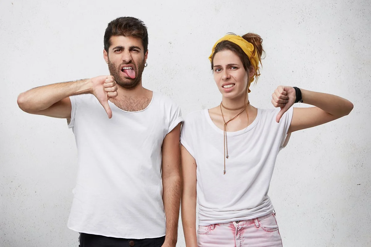 annoyed-disgusted-young-european-couple-wearing-stylish-clothing-expressing-dislike-disapproval-disrespect-disregard-with-gestures-showing-thumbs-down-grimacing.jpg?type=w1200