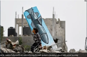 15 06 2023 A Palestinian girl sits on the remains of a destroyed house, next to a drawing of a missile by Hussein Abu Sadeq, in Deir Al-Balah, central Gaza Strip..JPG