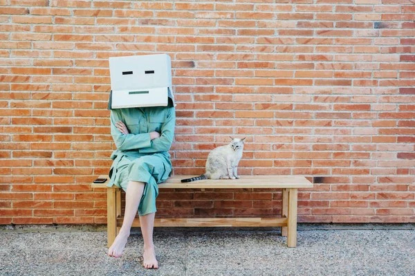 woman-sitting-on-bench-with-cat-in-front-of-brick-wall-with-serious-face-on-.jpg?type=w1600