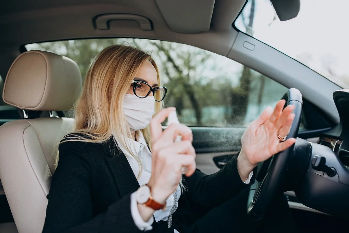 business-woman-protection-mask-sitting-inside-car-using-antiseptic.jpg?type=w1200