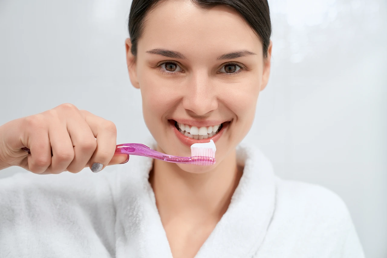 woman-holding-pink-toothbrush-with-toothpaste-in-b-2022-06-02-08-12-24-utc.JPG