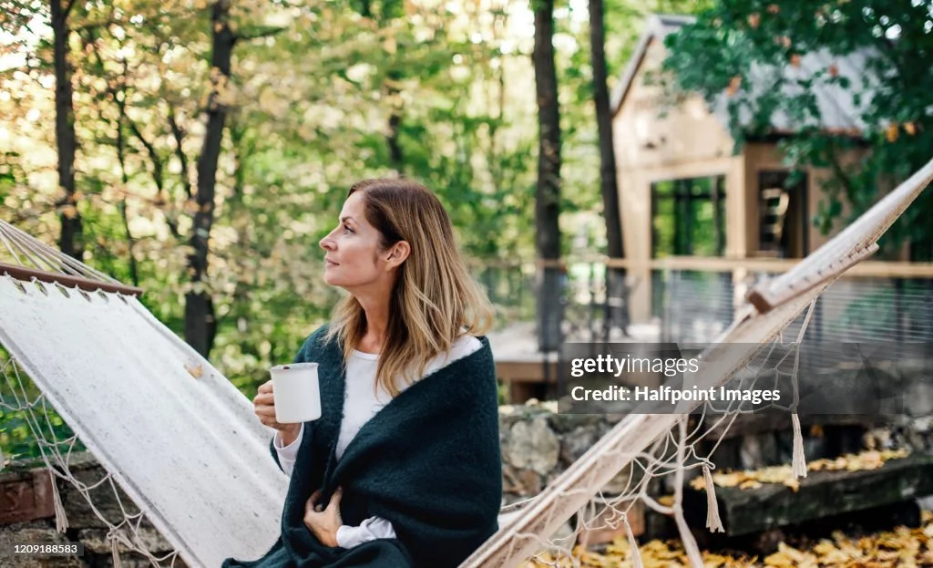 a-mature-woman-sitting-on-hammock-outdoors-in-front-of-a-tree-house.jpg?s=1024x1024&w=gi&k=20&c=4CACM1b6CTaOle-QT_ZmMXmqMPUxBh4tOqo_SNp6QKE=