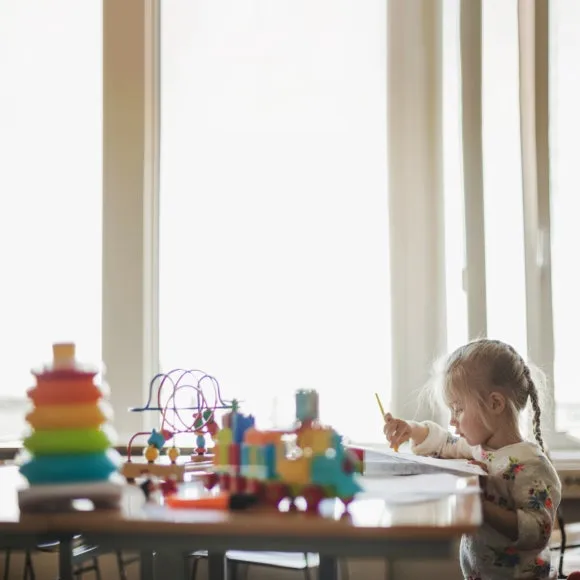 little-girl-sitting-table-with-toys.jpg?type=w580