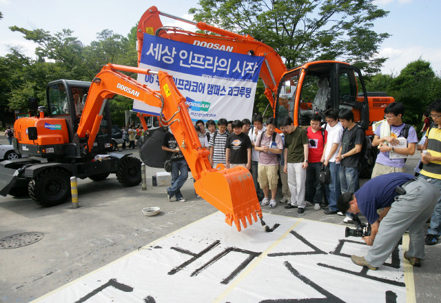10대 그룹 중 한 곳인 두산그룹의 계열사인 두산인프라코어가 2006년 한 대학 캠퍼스에서 중장비로 붓글씨를 쓰며 회사 홍보에 나선 모습. 두산인프라코어는 얼마 전 회사가 어렵다며 신입사원에게도 사표를 내라고 요구했다가 그룹 회장이 사과를 하기도 했다. 구조조정은 여러 사람을 고통에 빠뜨리기도 하지만 기업을 수렁에서 건져주는 ‘양날의 칼’이다.  연합뉴스