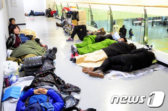 제주지역에 많은 눈이 내려 제주공항이 전편 결항된 가운데 24일 제주국제공항 대합실에 승객들이 종이상자를 펴고 잠을 자고 있다.2016.1.24/뉴스1 © News1 이석형 기자