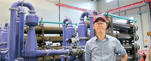 △ 김찬호 에스엔에스에너지 대표가 직접 개발한 폐수열 회수 설비 앞에서 포즈를 취하고 있다. [사진 제공〓에스엔에스에너지]