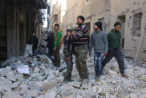A Syrian man comforts a boy amid the rubble of buildings following a reported air strike on the rebel-held neighbourhood of al-Kalasa in the northern Syrian city of Aleppo, on February 4, 2016 / AFP