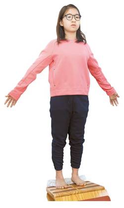 머리·어깨·등·종아리·발꿈치를 벽에 붙인 다음 10분 동안 유지하는 전신 스트레칭 중인 엄다연양. 팔을 45도로 벌린 후 손등과 엄지손가락까지 붙여야 한다. 척추를 정렬하고, 구부정한 자세를 바르게 펴주는 전신 교정 효과가 있다.