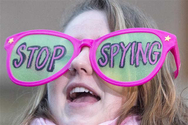 23일 미국 워싱턴 연방수사국(FBI) 건물 앞에서 한 여성이 “스파이 짓 멈추라”고 쓰인 안경을 착용하고 애플을 지지하는 시위를 하고 있다. 워싱턴/EPA 연합뉴스