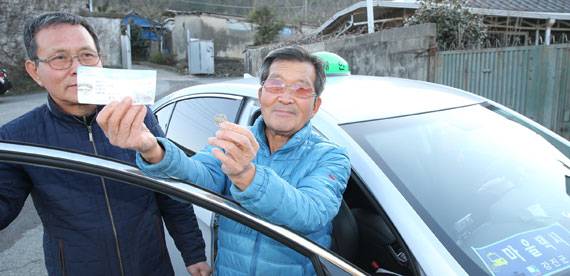 전남 강진군 칠량면에 사는 조남연씨(75·오른쪽)가 이달 초 100원 택시를 타고 귀가한 뒤 ‘택시 이용권’과 요금 100원을 들어보이고 있다. [프리랜서 장정필]