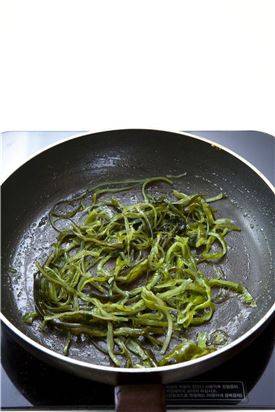 3. 미역줄기를 반으로 나누어 반은 들기름을 두르고 볶다가 소금으로 간하고 깨소금을 넣어 볶는다.