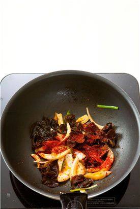 4. 달군 팬에 고추기름을 두르고 대파와 마늘을 살짝 볶다가 양파, 목이버섯을 넣어 볶고 고춧가루, 청주를 넣는다.