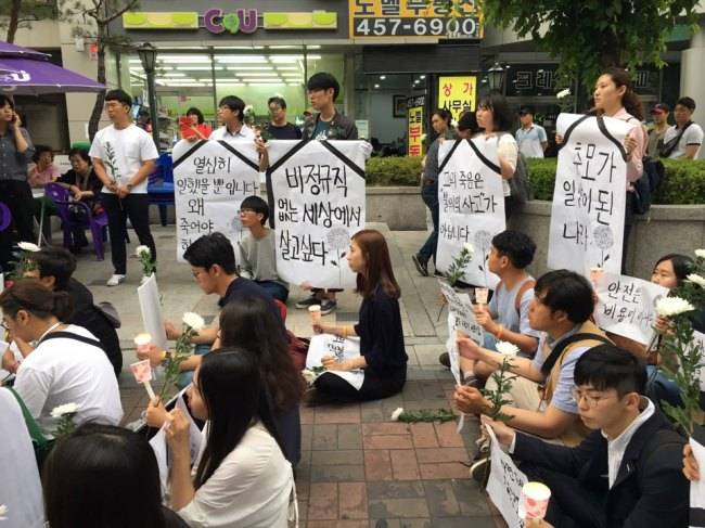 Mourners hold up posters reading "Human lives should come first before money" and "Stop outsourcing safety-related work" outside Guui Station, Saturday. (Ock Hyun-ju/The Korea Herald)