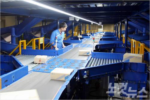 컨베이어에 흘러가는 택배박스를 지정된 구역으로 밀어 지역별로 분류하는 휠소터 장비 (사진=CJ대한통운 제공)