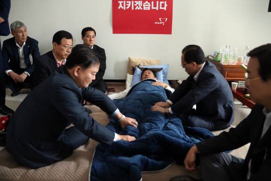 새누리당 이정현 대표의 생일인 1일 오전 국회 대표실을 찾은 민경욱, 이현재 등 의원들이 엿새째 단식 농성을 이어가고 있는 이 대표의 다리를 주무르고 있다. /연합뉴스