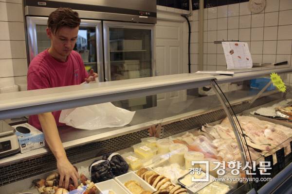 9월14일 노르웨이 서부 해안도시 올레순의 한 생선가게에서 직원이 해산물을 포장하고 있다. 매대에는 노르웨이 사람들이 가장 즐겨 먹는 생선인 대구, 연어, 핼리버트, 늑대물고기 어묵 등이 손님을 기다리고 있다. 올레순 시내 부둣가는 과거 매일 아침이면 배에서 잡아온 생선을 파는 노천시장이 열렸지만 이제 시장은 사라지고 관광객을 위한 요트들이 즐비하다. 올레순 시내에서 신선한 해산물을 구하려면 이 가게를 찾거나 차로 10~20분 거리의 대형마트로 가야 한다.