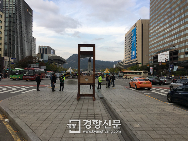 지난 29일 오후 3시쯤 서울 광화문 사거리 한복판에 설치미술 작품으로 보이는 ‘단두대’가 등장했다. 단두대 뒤로 이순신 장군 동상과 함께 멀리 청와대가 보인다. 사진  독자 제공