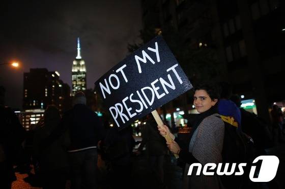 한 여성이 9일(현지시간) 뉴욕 시에서 "내 대통령은 아니다"는 구호가 적힌 판넬을 들고 있다. © AFP=뉴스1