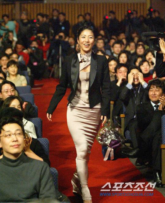 2003년 청룡영화상에서 여우주연상을 수상한 장진영이 본인의 이름이 호명되자 밝은 표정으로 무대에 나서고 있다. 옆에서 송강호가 축하의 박수를 보내고 있다.