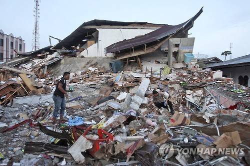 7일 규모 6.5의 강진이 덮친 인도네시아 서부 아체주 피디에 자야 지역에서 현지 경찰이 폐허가 된 건물 주변을 살피고 있다.[AP=연합뉴스자료사진]