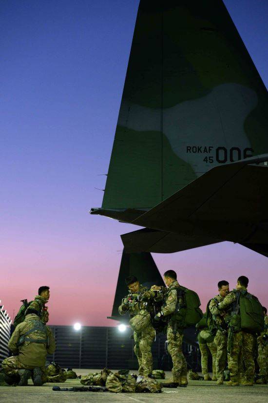 탑승 전 수송기 후미에서 장비를 교차 점검하고 있는 요원들.